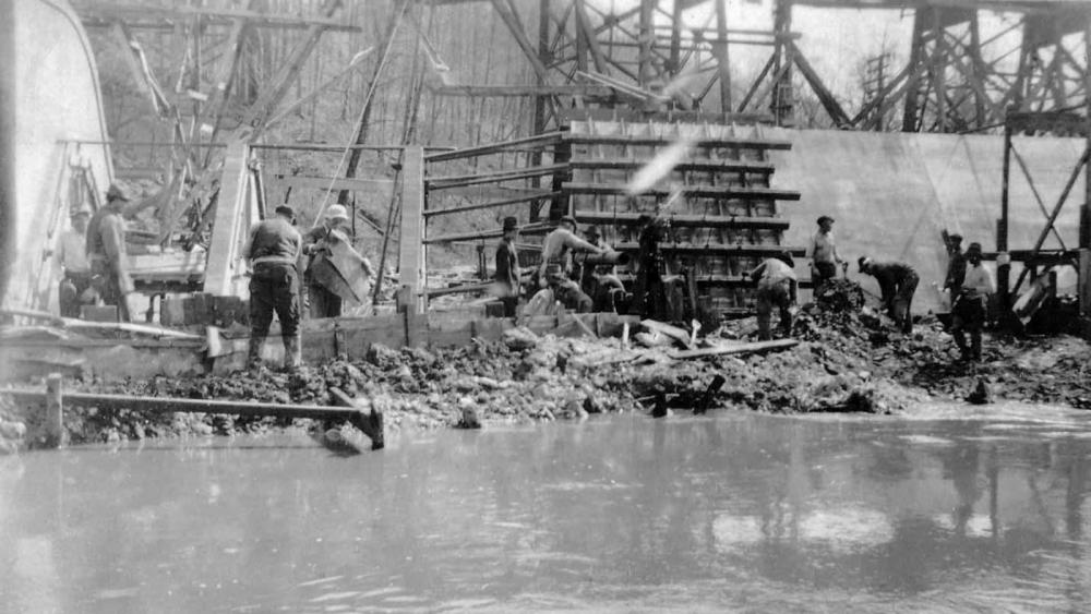 Black and white photo from 1940 showing workers constructing the Lake Accotink dam with wooden scaffolding along the waterfront